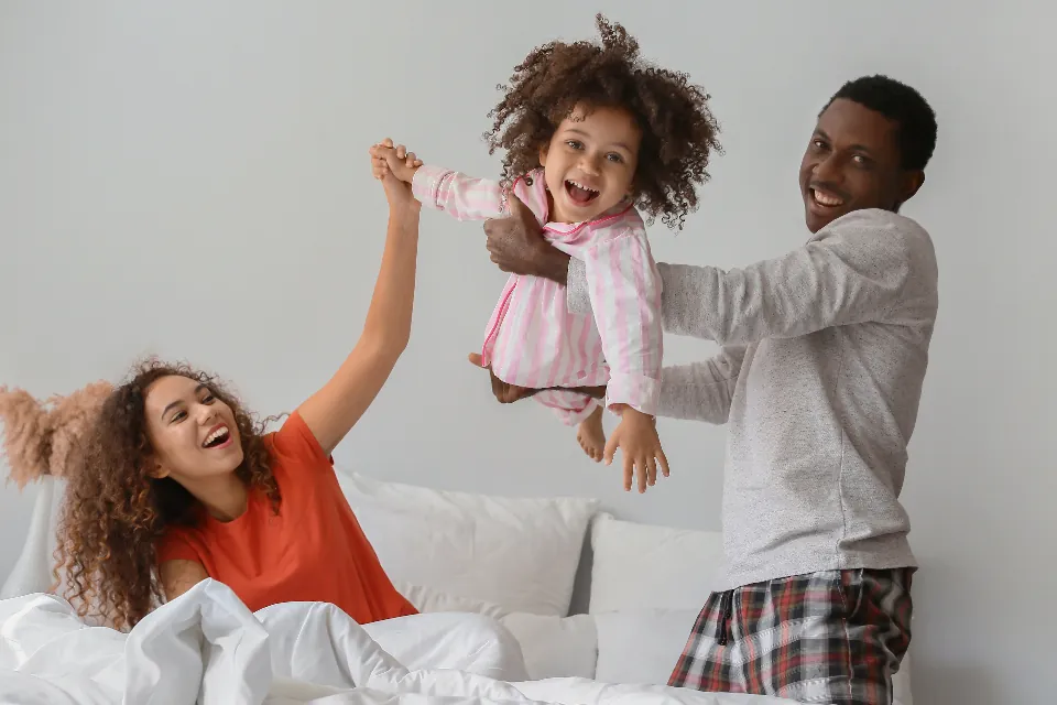 Familia en pijama de cuadros jugando sobre la cama